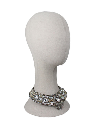  unlabeled neck ring. features multiple rhinestones with marquise and round cuts. smaller gold and silver beads, and metal base. 3 strings of rhinestones are tiered in the center