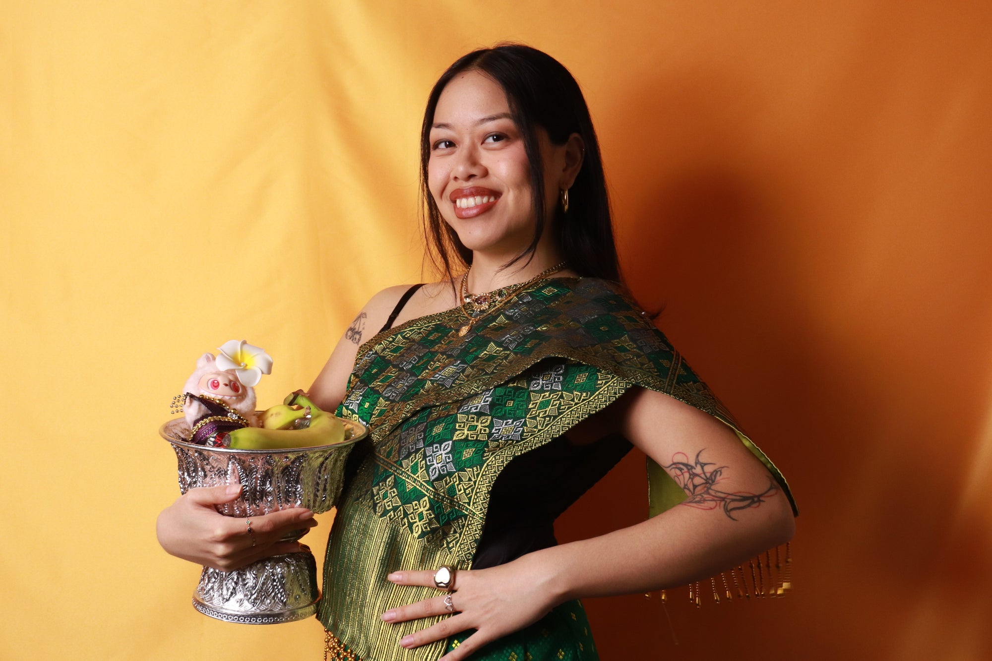 model posing with bowl of fruit in celebratory traditional Lao sinh style (traditional dress) for the month of TLC New Year (Thai Lao Cambodian New Year)