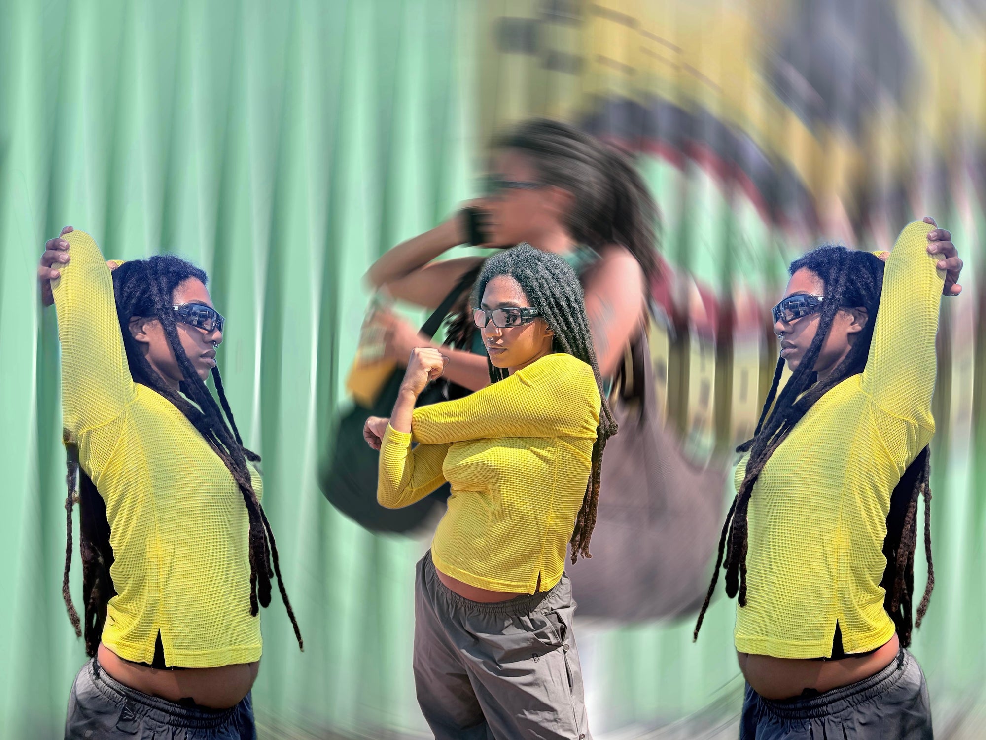 A person wearing a bright yellow long-sleeve cropped top and gray pants poses in front of a green curtain backdrop, with a blurred duplicate figure behind them.