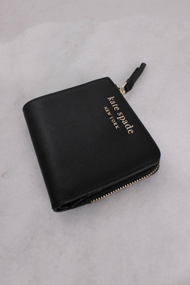 three-quarter front angle kate spade bifold wallet featuring 'kate spade' 'new york' gold-toned text and l-zip compartment.
