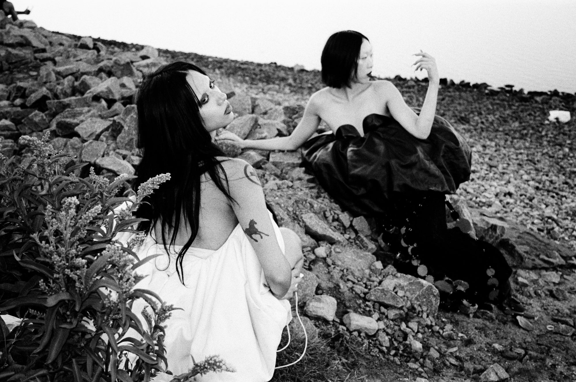 spooky couture black/white editorial shot of models posing on rock rubble