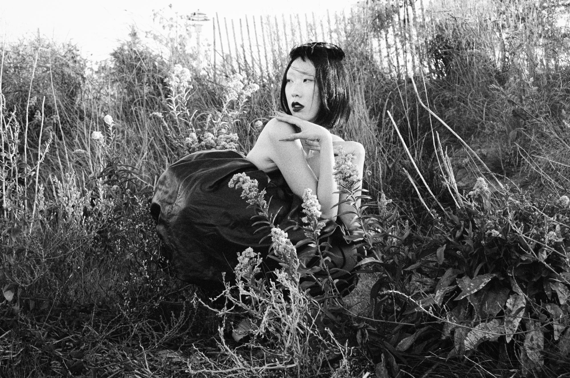 Person sitting in a field of tall grass and wildflowers